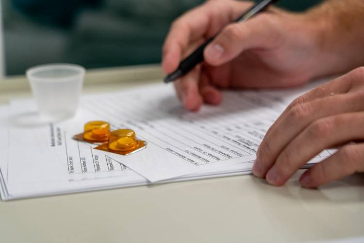 Medication with medical worker marking it off on a sheet of paper