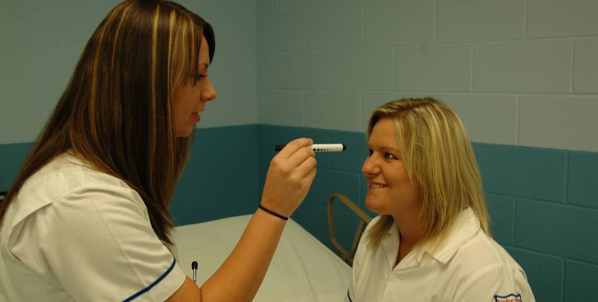 Student checking a patient's eyes