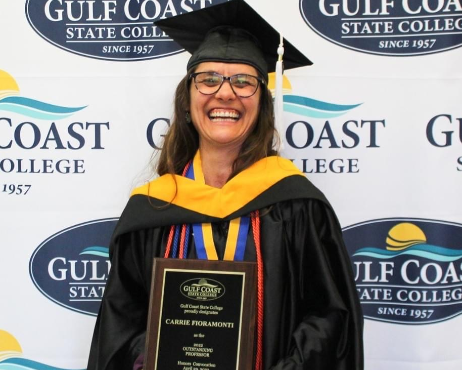 An instructor in a cap and gown with tassels