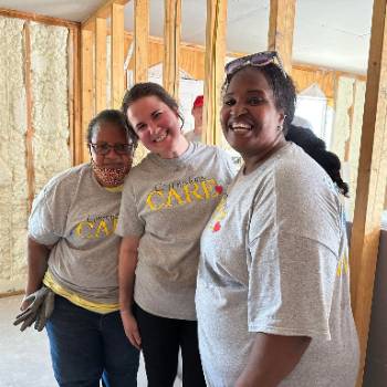 GCSC students and staff member Janeka Peace smiling while installing dry wall