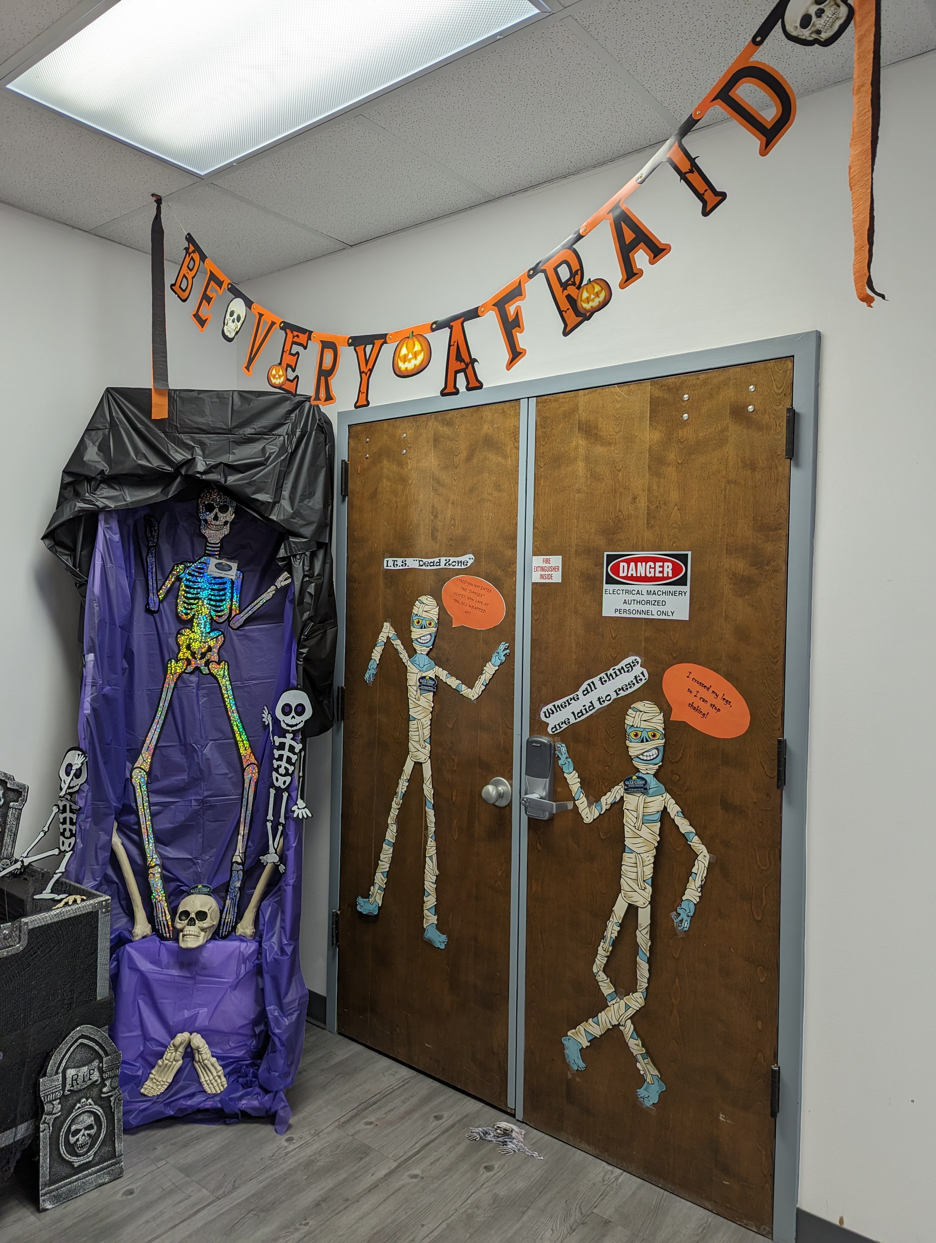 Information Technology Services, ITS Halloween Decorations in GCSC's ITS Building. Skeletons and mummies in a coffin.
